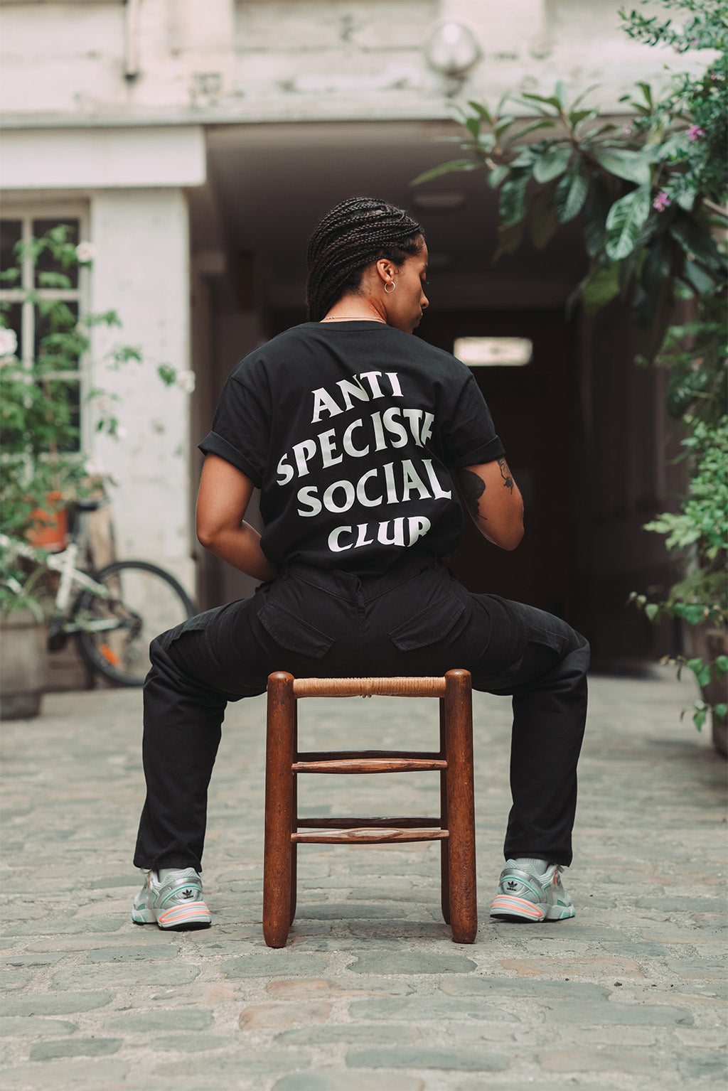 Mannequin femme de dos portant un t-shirt noir avec une sérigraphie blanche Anti Spéciste Social Club.