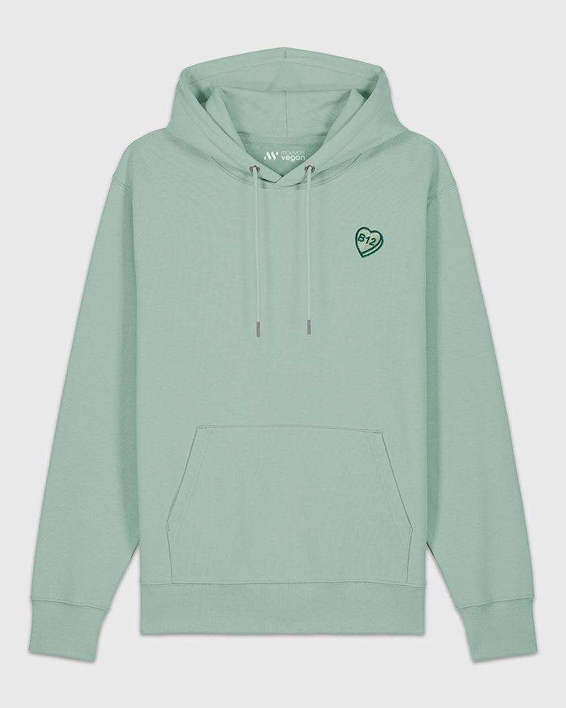 Hoodie vert sauge avec une broderie verte en forme de comprimé de B12 en coeur.