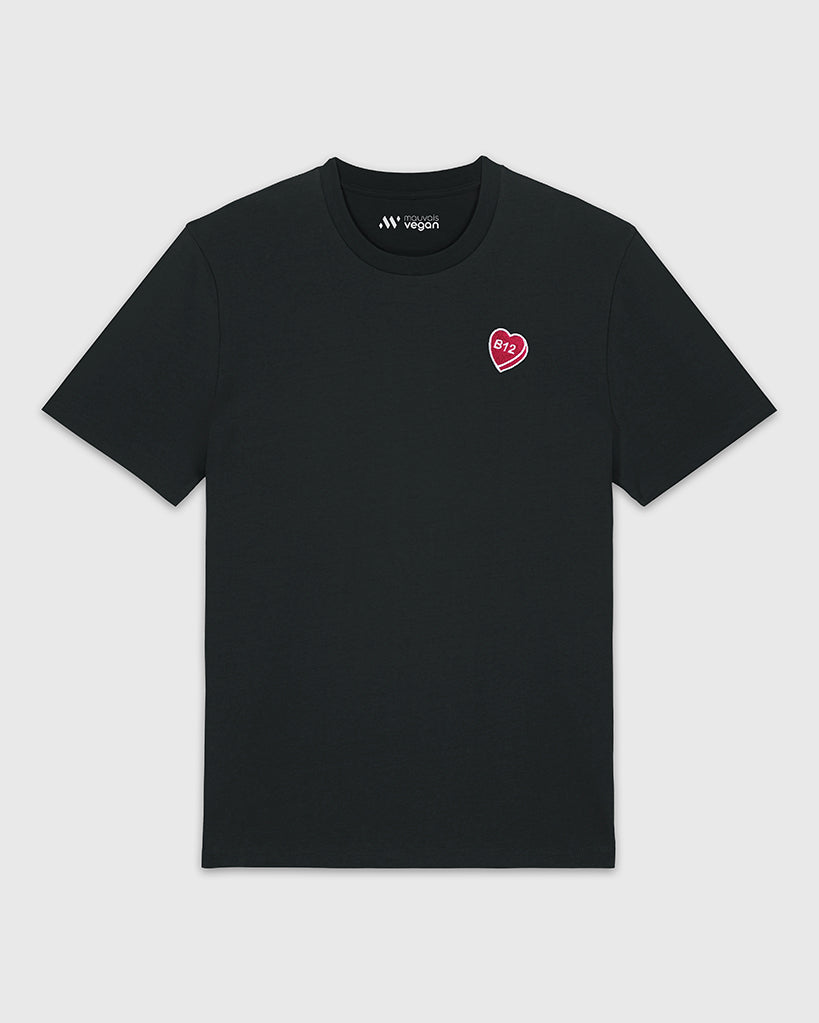 T-shirt noir avec une broderie fuchsia en forme de comprimé de B12 en coeur.