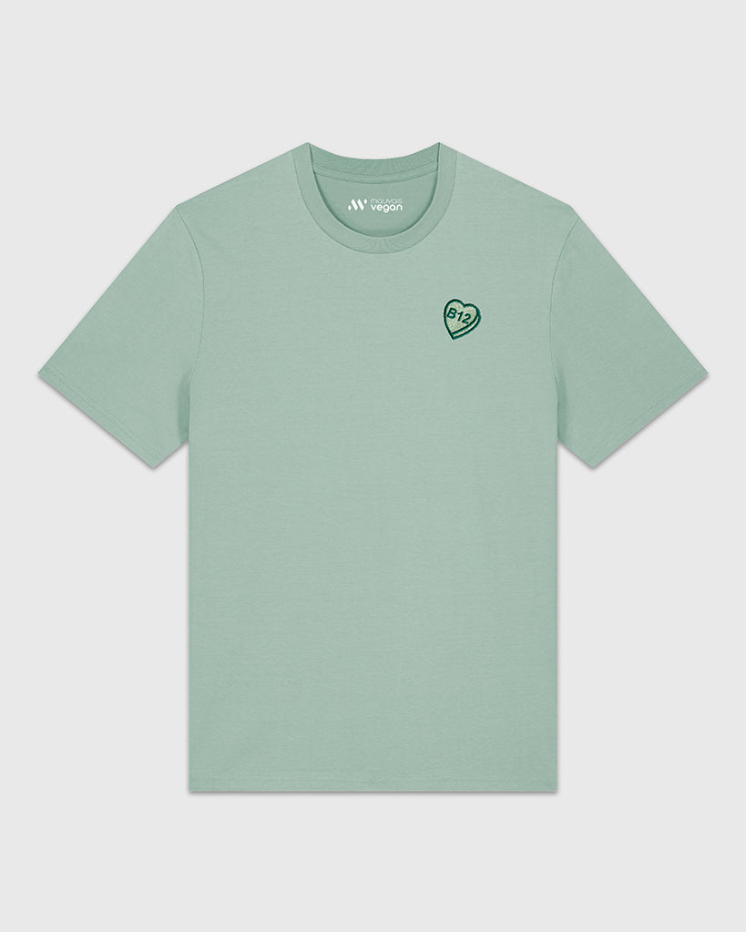 T-shirt vert sauge avec une broderie verte en forme de comprimé de B12 en coeur.