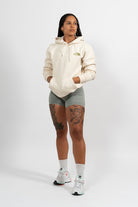 Mannequin femme portant un hoodie beige avec une broderie khaki The Plant Based.